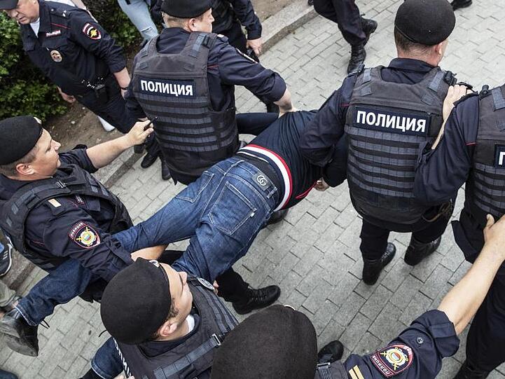 Polizisten tragen einen festgenommenen Demonstranten weg. Mehr als 200 Menschen sind in Moskau festgenommen worden.