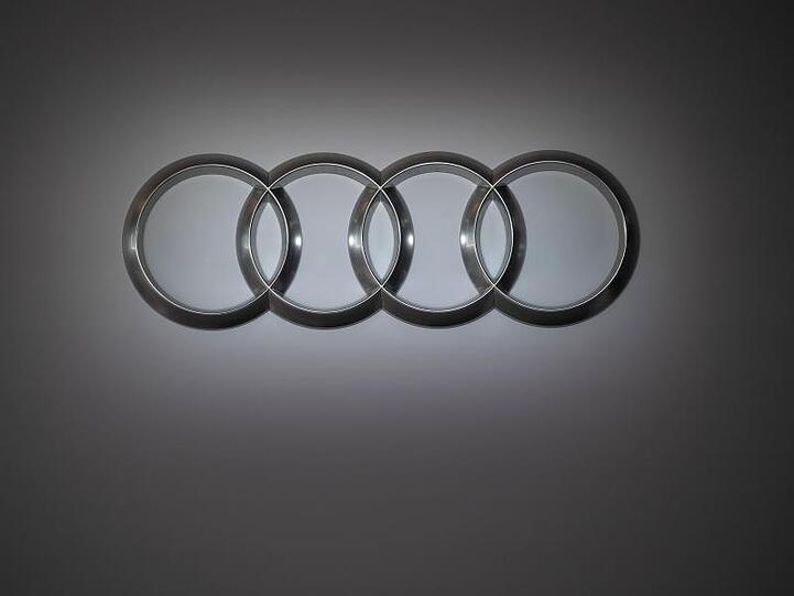Das Audi-Logo zeigt vier miteinander verbundene Kreise vor dem Hintergrund einer grauen Wand. Foto: Marijan Murat/dpa/Archivbild
