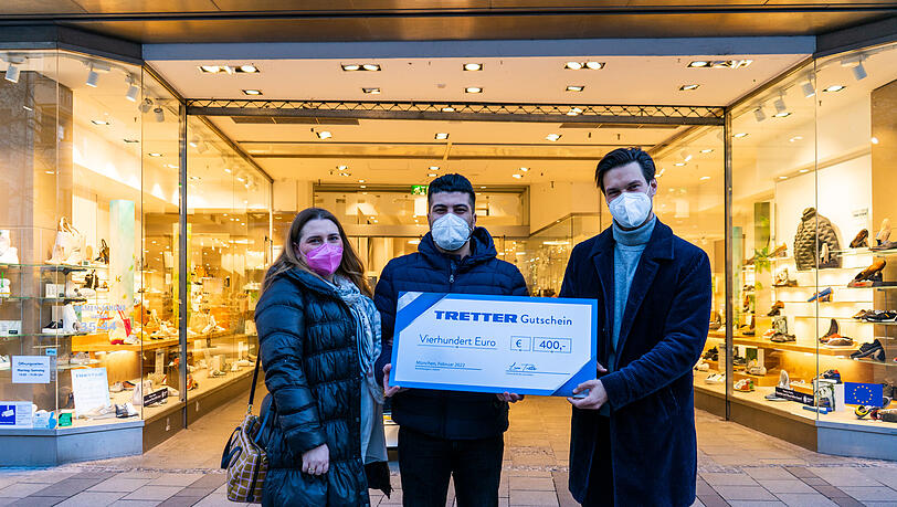 Luca Tretter (rechts) überreicht Melissa und Ali einen großzügigen Gutschein, mit dem die Brautleute danach in der TRETTER-Filiale in der Neuhauser Straße 39 einkaufen gehen. So macht das besonders Spaß!