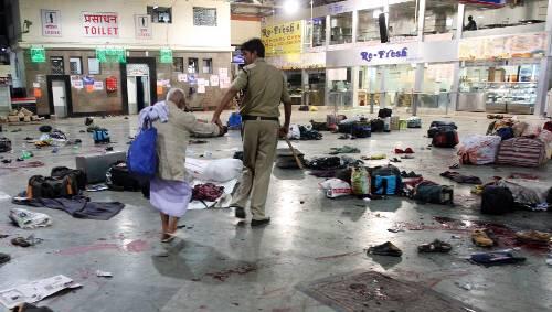 An der Hand führt ein Polizist einen alten Mann aus dem Chaos von Trümmern und Blut, das ein Terroranschlag auf den überfüllten Hauptbahnhof von Bombay hinterlassen hat. An der Hand führt ein Polizist einen alten Mann aus dem Chaos von Trümmern und Blut, das ein Terroranschlag auf den überfüllten Hauptbahnhof von Bombay hinterlassen hat.