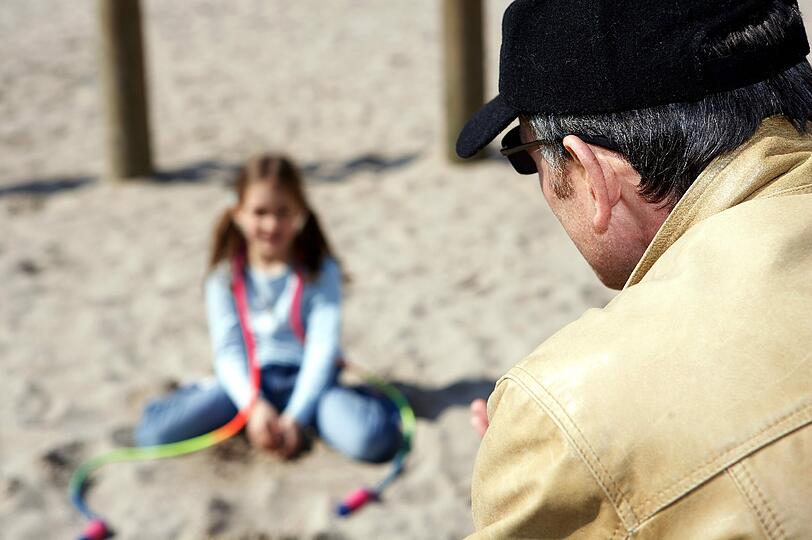 Ein Mann spricht auf einem Spielplatz in einem Neubaugebiet  ein kleines Mädchen an (gestelltes Illustrationsfoto)