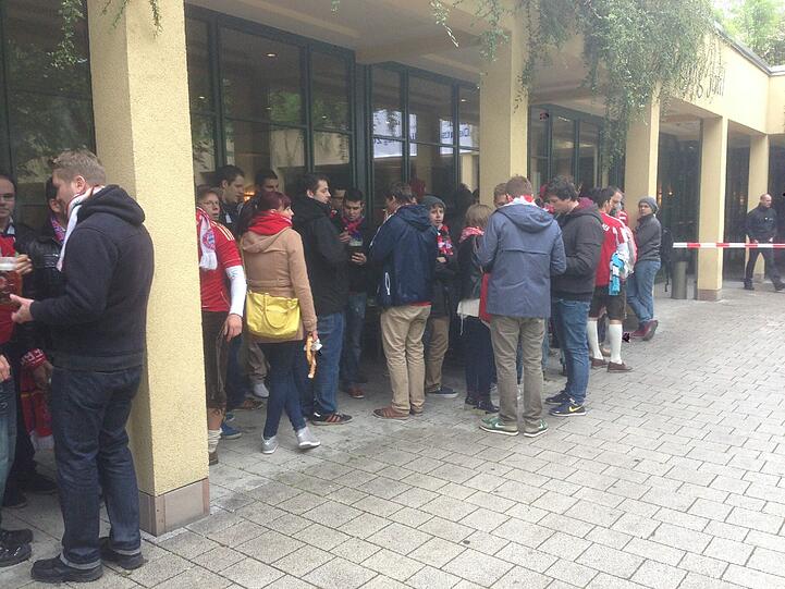 Die ersten Fans warten bereits seit 12 Uhr. Geöffnet wird der Innenraum aber erst um 19 Uhr! Dafür Lederhosen, Trikots und Fahnen en masse. BVB-Fans sind hier kaum zu sehen.