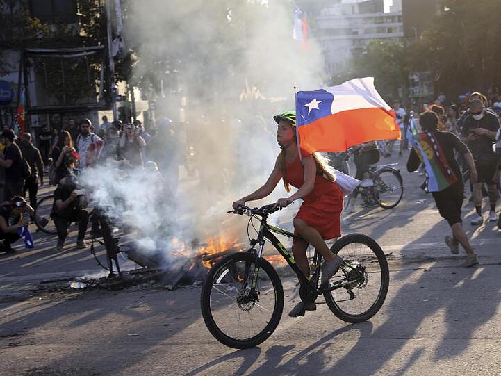 Bei einer Protestaktion gegen die Regierung hat eine junge Frau in Santiago ihr Fahrrad mit der chilenischen Flagge ausgestattet.