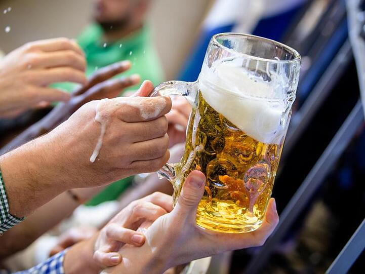Besucher greifen im Paulaner-Festzelt nach einem Bierkrug. Foto: Matthias Balk