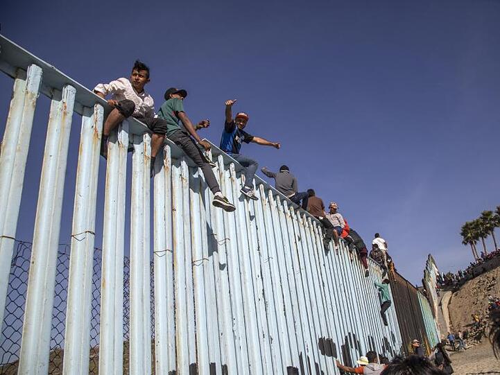Migranten aus Mittelamerika sitzen in Tijuana auf dem Grenzzaun zwischen Mexiko und den USA.