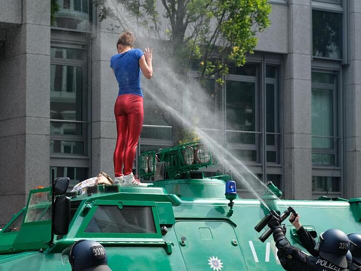 Konfrontation: Eine junge Frau weicht auch nach einem massiven Pfefferspray-Einsatz nicht von der Motorhaube des Polizeifahrzeugs.