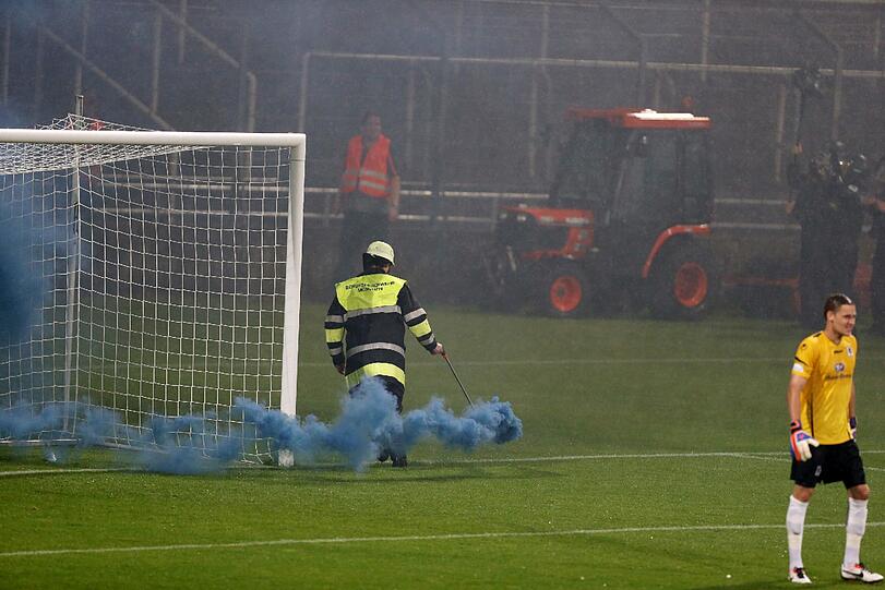 Ein Feuerwehrler entfernt eine Rauchbombe beim kleinen Derby im Grünwalder Stadion