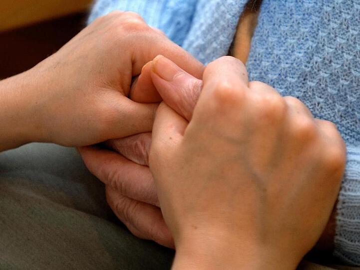 Eine Pflegerin hält die Hand eines Senioren. Foto: Norbert Försterling/dpa/Symbolbild
