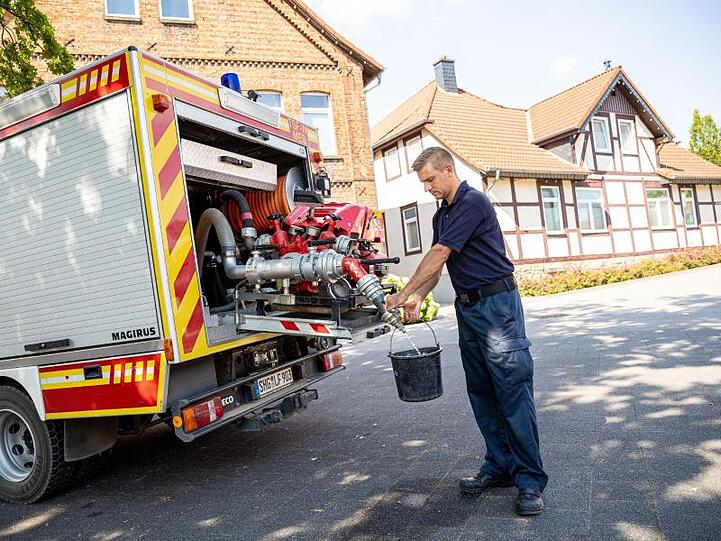 Einsatzkräfte der Freiwilligen Feuerwehr zapfen Löschwasser aus dem Tank eines ihrer Einsatzfahrzeuge.