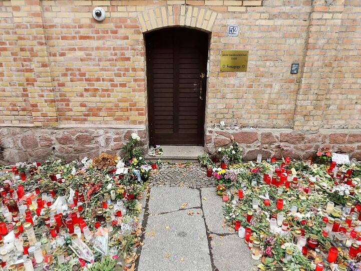Nur noch ein schmaler Weg führt zwischen den Blumen und Kerzen zur Tür der Synagoge Halle.
