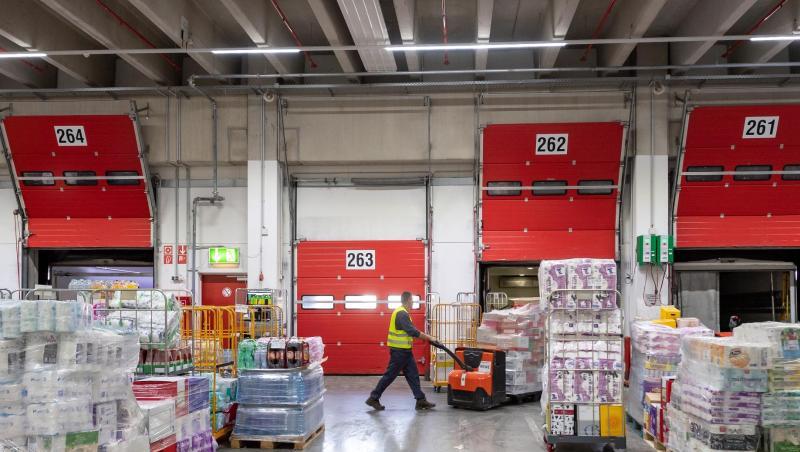 Ein Mann schiebt eine mit Waren bepackten Palettenheber durch das Zentrallager REWE Süd. Foto: Peter Kneffel/dpa/Symbolbild Ein Mann schiebt eine mit Waren bepackten Palettenheber durch das Zentrallager REWE Süd. Foto: Peter Kneffel/dpa/Symbolbild