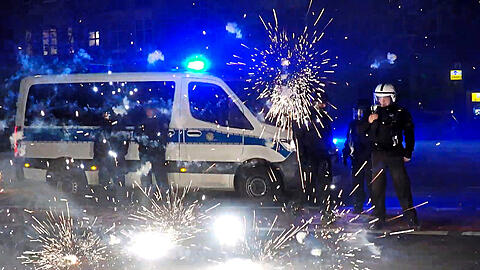 Polizeibeamte stehen am Silvesterabend in Berlin hinter explodierendem Feuerwerk.