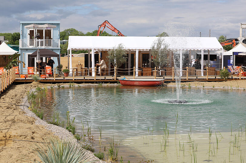 Hinter der Freiluft-Bar am See ist Baustelle &ndash; das kann man am Bagger sehen, der hinter der Lounge herauslugt.