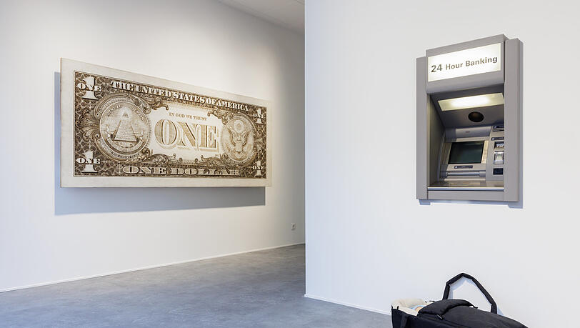 Eine Tragetasche samt Baby steht vor dem Geldautomaten. Hat da jemand sein Kind vergessen, oder spekuliert er oder sie, dass sich ein freundlicher Mitmensch erbarmt und dem „Modern Moses“ ein gutes neues Zuhause schenkt? Was zählt, ist das Geld. Tom Sachs bringt das mit seiner überdimensionalen „One Dollar“-Note prima zum Ausdruck. Eine Tragetasche samt Baby steht vor dem Geldautomaten. Hat da jemand sein Kind vergessen, oder spekuliert er oder sie, dass sich ein freundlicher Mitmensch erbarmt und dem „Modern Moses“ ein gutes neues Zuhause schenkt? Was zählt, ist das Geld. Tom Sachs bringt das mit seiner überdimensionalen „One Dollar“-Note prima zum Ausdruck.