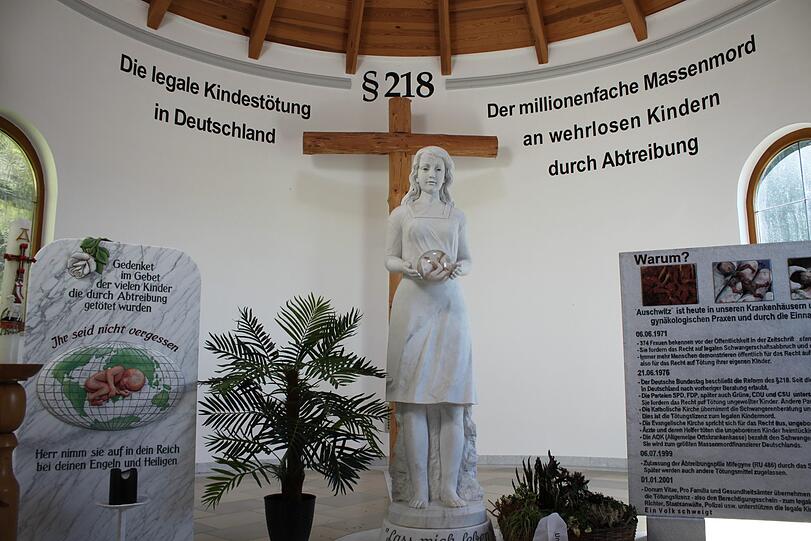 Der Innenraum der Pösinger Kapelle: Auf einer Tafel steht "Auschwitz ist heute in unseren Krankenhäusern" (rechts).