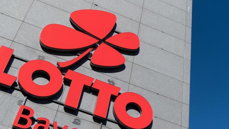 Das Logo und der Schriftzug "Lotto Bayern" sind an dem Firmengebäude der Lottozentrale in München zu sehen.