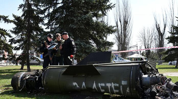 Ukrainische Soldaten während Ermittlungsarbeiten neben einem Fragment einer Tochka-U-Rakete mit der russischen Aufschrift "Für Kinder" nahe des Bahnhofs in Kramatorsk.