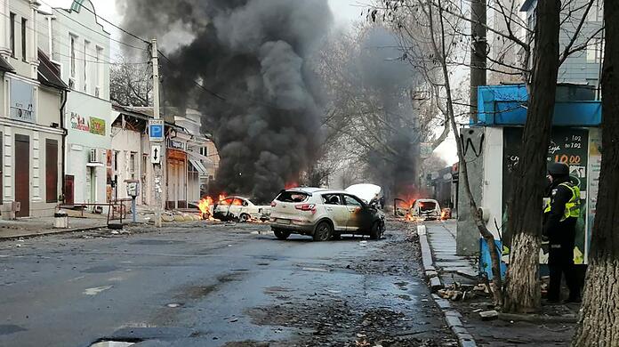 Autos brennen nach einem russischen Raketenangriff auf das Stadtzentrum von Cherson.