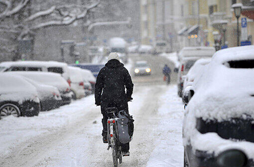 Der Winter hat Bayern fest im Griff. Eine Radfahrerin fährt durch den frisch gefallenen Schnee in München.