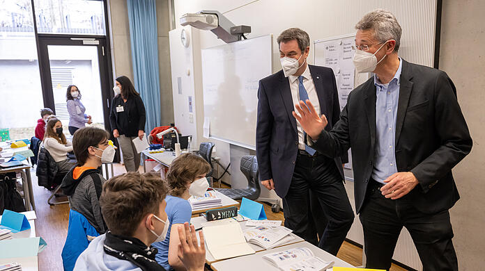 Markus Söder (links, CSU) Ministerpräsident von Bayern, und Michael Piazolo, (Freie Wähler) Staatsminister für Unterricht und Kultus, verabschieden sich von Kindern aus der Ukraine, die sie in einer Willkommensklasse des Gymnasium Trudering besucht haben.