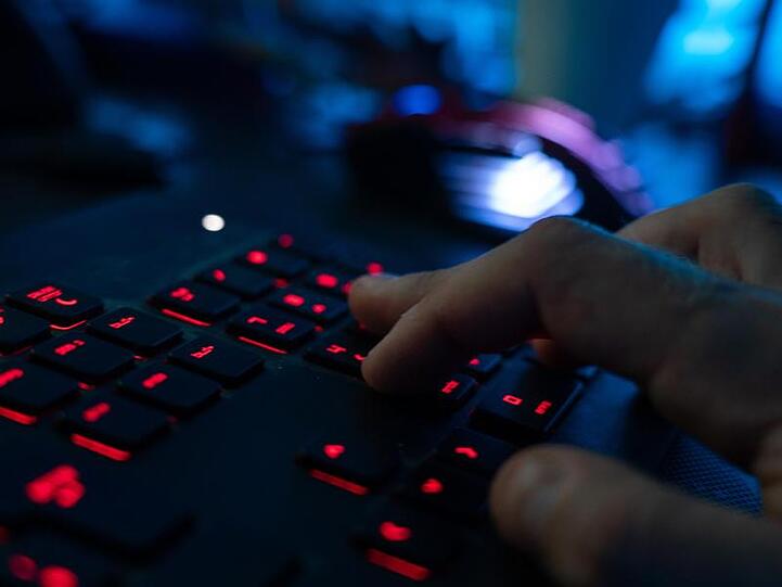 Finger tippen auf einer beleuchteten Tastatur.