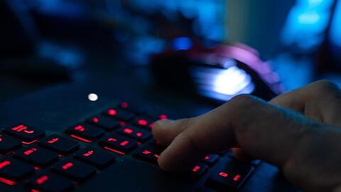 Finger tippen auf einer beleuchteten Tastatur.