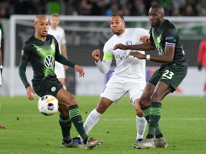 Wolfsburgs Marcel Tisserand (l) und Josuha Guilavogui (r) kämpfen mit Gents Vadis Odjidja um den Ball.
