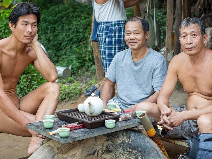 Duong (l) trinkt mit zwei Männern Tee.
