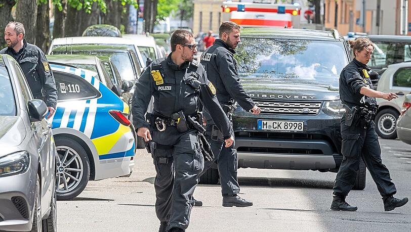 Polizeibeamte suchen in einer Straße in Schwabing zwischen und unter den parkenden Autos eine Waffe. Polizeibeamte suchen in einer Straße in Schwabing zwischen und unter den parkenden Autos eine Waffe.