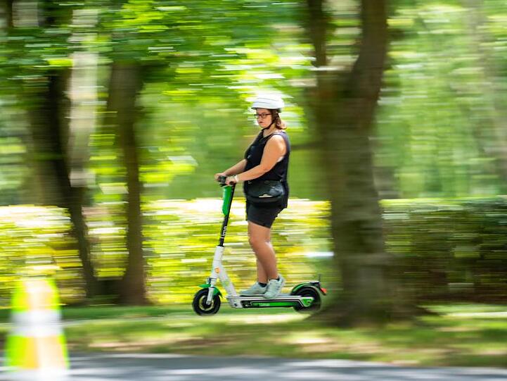Eine Frau fährt einen E-Scooter. Foto: Frank Rumpenhorst/dpa/Archiv