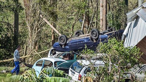 Ein Mann schiebt nach Überschwemmungen eine Schubkarre an zerstörten Autos vorbei.