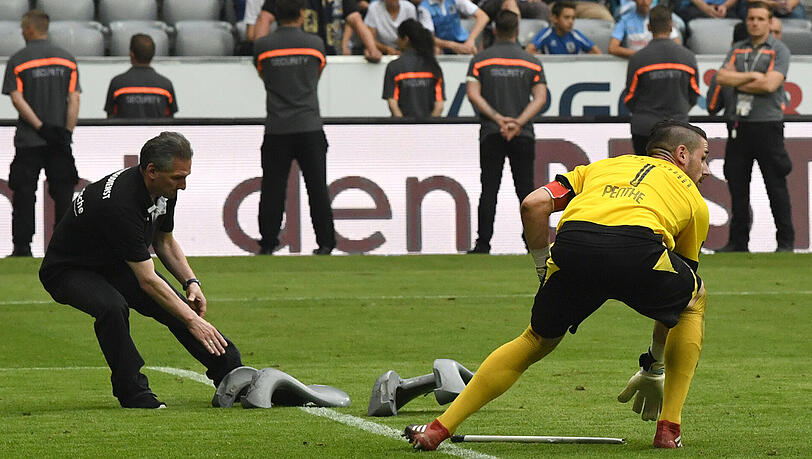 Ein Ordner und Torwart Philipp Pentke von Regensburg heben Sitzschalen auf, die auf das Spielfeld geworfen wurden. Ein Ordner und Torwart Philipp Pentke von Regensburg heben Sitzschalen auf, die auf das Spielfeld geworfen wurden.