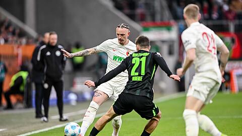 Augsburgs Marius Wolf spielt den Ball an Joakim Maehle von Wolfsburg vorbei.