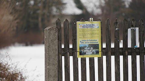 Ein Schild der Bürgerinitiative &bdquo;Rettet die Unnützwiese&ldquo;. Es hängt an einem Zaun am Rande der umkämpften Grünfläche.
