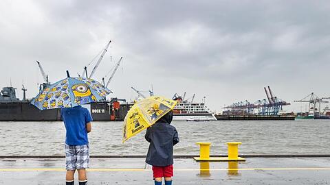 Mit bunten Regenschirmen schützten sich zwei Jungen im Hafen Hamburg vor dem Regen. Nach vielen trockenen, sonnigen Tagen regnet es wieder in der Hansestadt.