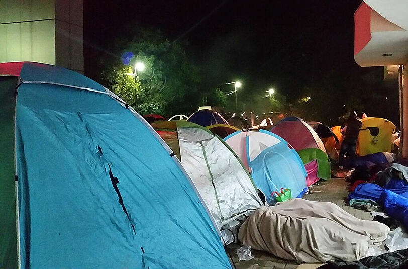 Weil es immer wieder regnet, haben Helfer Zelte aufgestellt, in denen die Menschen Schutz suchen können. Auch dazwischen schlafen Flüchtlinge, eingemummt in Decken.