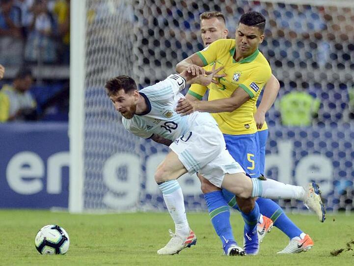 Lionel Messi versucht sich gegen den Brasilianer Casemiro (r) durchzusetzen.