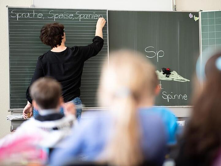 Eine Lehrerin schreibt an die Tafel. Foto: Sebastian Gollnow/dpa/Archivbild