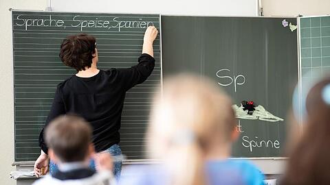 Eine Lehrerin schreibt an die Tafel. Foto: Sebastian Gollnow/dpa/Archivbild