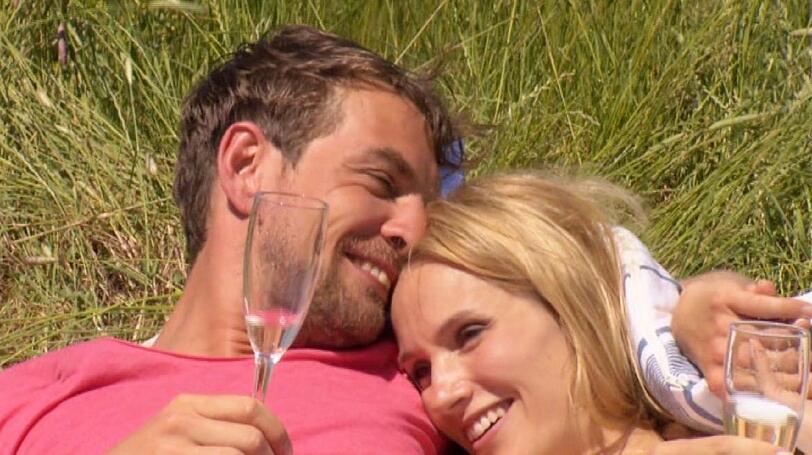 Anna und Marvin kuscheln nach ihrem Skydiving-Sprung auf einer Wiese.