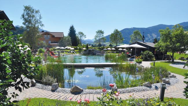 Idyll vor der Tür: Im Garten des Vier-Sterne-Hotels „Ferienwelt Kesselgrub“ in Altenmarkt (Salzburger Pongau) liegt auch dieser solarbeheizte Naturbadesee – herrlich für einen Familienurlaub.