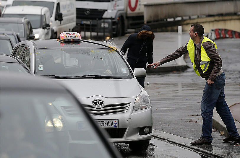 Ein Taxifahrer, der nicht am Protest teilnimmt, wird von einem Demonstraten mit Eiern beworfen.