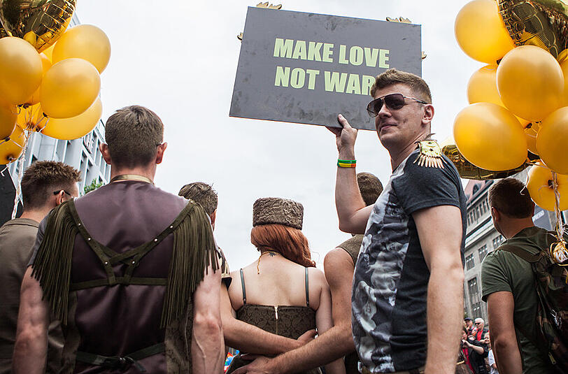Ein Mann hält ein Plakat mit der Aufschrift "MAKE LOVE NOT WAR".