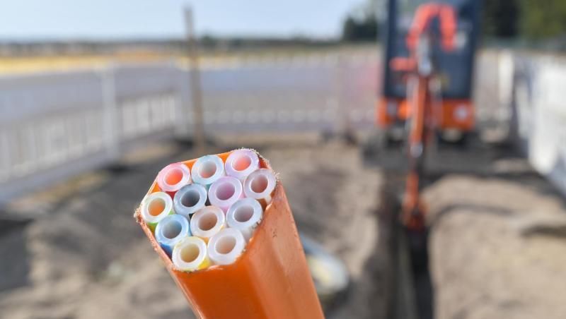 Farbige Leerrohre, in die später Glasfaserkabel verlegt werden, ragen aus dem Graben einer Baustelle. Farbige Leerrohre, in die später Glasfaserkabel verlegt werden, ragen aus dem Graben einer Baustelle.