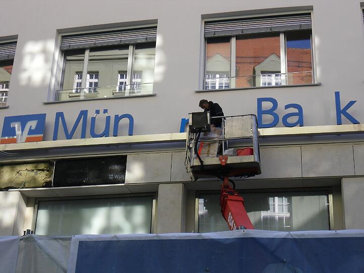Hier wird der Schriftzug der Münchner Bank montiert.