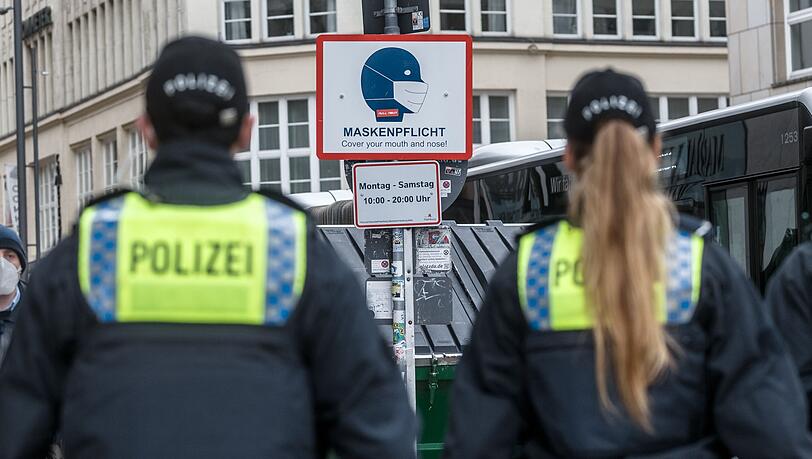 Polizisten patrouillieren in einer Stadt, um die Maskenpflicht zu kontrollieren.
