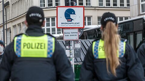 Polizisten patrouillieren in einer Stadt, um die Maskenpflicht zu kontrollieren.