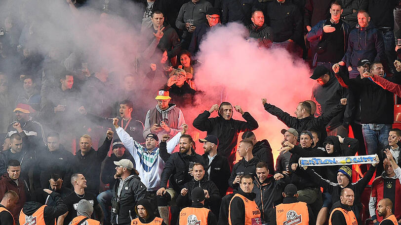 Deutsche Zuschauer zünden Pyrotechnik, verhöhnen den DFB und grölen ausländerfeindliche Parolen.