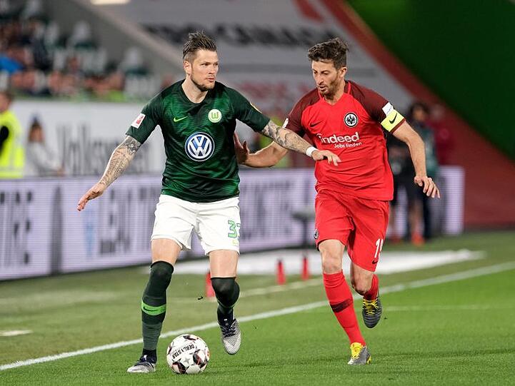 Der Wolfsburger Daniel Ginczek (l) wird von Frankfurts Kapitän David Abraham eng bewacht.