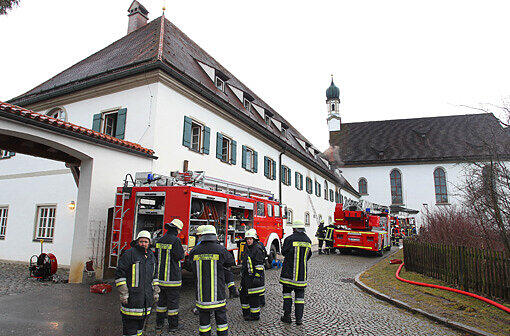 Einsatzkräfte der Feuerwehr stehen am Sonntagmorgen vor dem Franziskanerkloster in Füssen.
